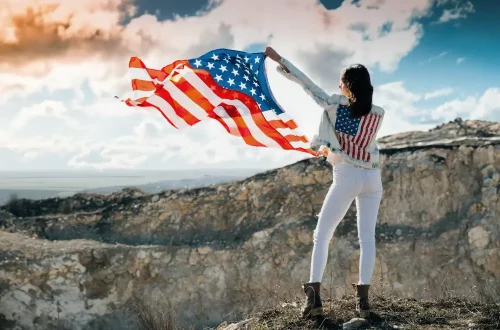 Con la ciudadania italiana puedo vivir en eeuu: Mujer levantando la bandera de Estados Unidos