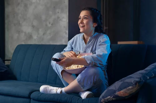 Los mejores filmes italianos en Netflix para ver hoy: Foto de una joven viendo películas y comiendo palomitas en casa
