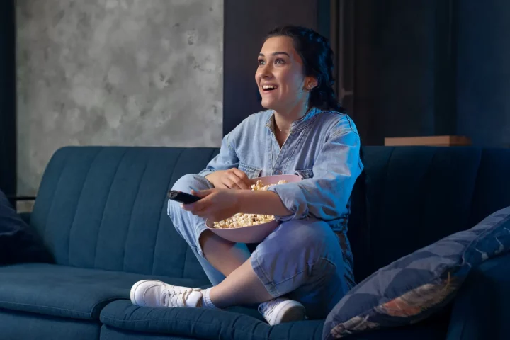 Los mejores filmes italianos en Netflix para ver hoy: Foto de una joven viendo películas y comiendo palomitas en casa